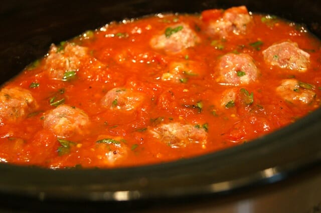 A slow cooker with marinara sauce with meatballs
