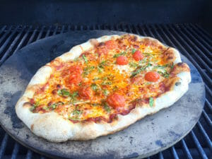 Pizza grilling on a pizza stone