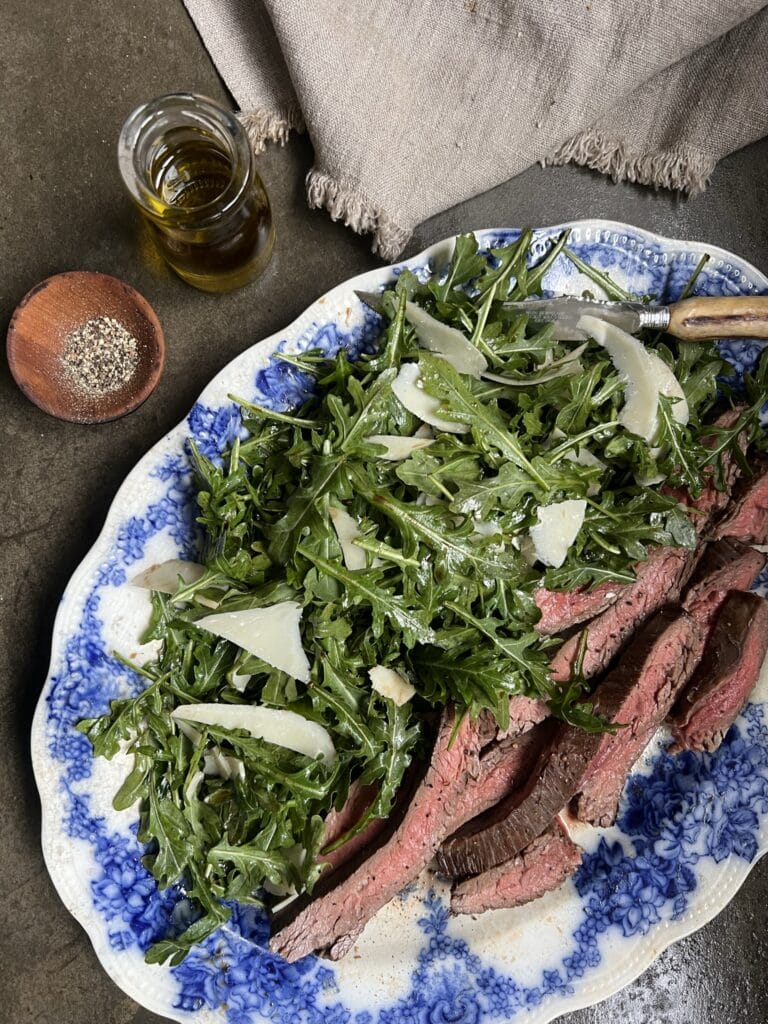 steak on arugula with balsamic and parmesan