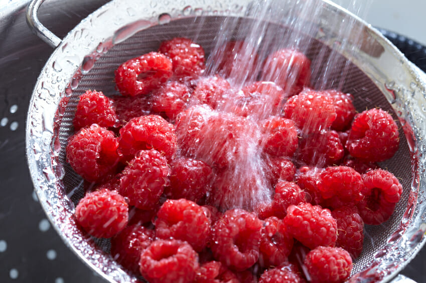 Fresh raspberries being washed and tips on how to buy, store, and use berries