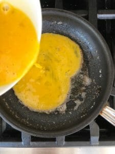 Pouring eggs into pan for omelet