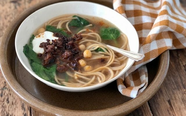 Aush, Afghan soup with noodles, chickpeas, spinach and ground meat with a check napkin