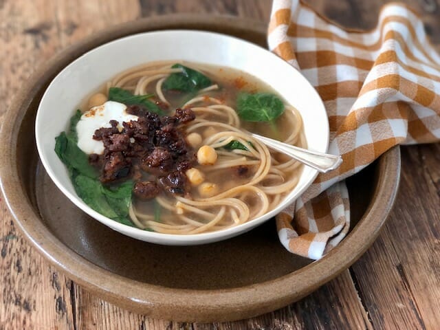 Aush, Afghan soup with noodles, chickpeas, spinach and ground meat with a check napkin