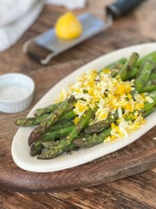 plate of roasted asparagus with egg and lemon and capers