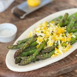 plate of roasted asparagus with egg and lemon and capers