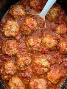 Turkey meatballs in a slow cooker with a white spoon