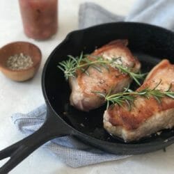 Pork chops in a cast iron skillet with rhubarb compote and rosemary