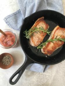 Pork chops in a cast iron skillet with rhubarb and rosemary