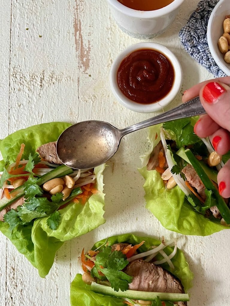 spooning dressing over pork lettuce wraps