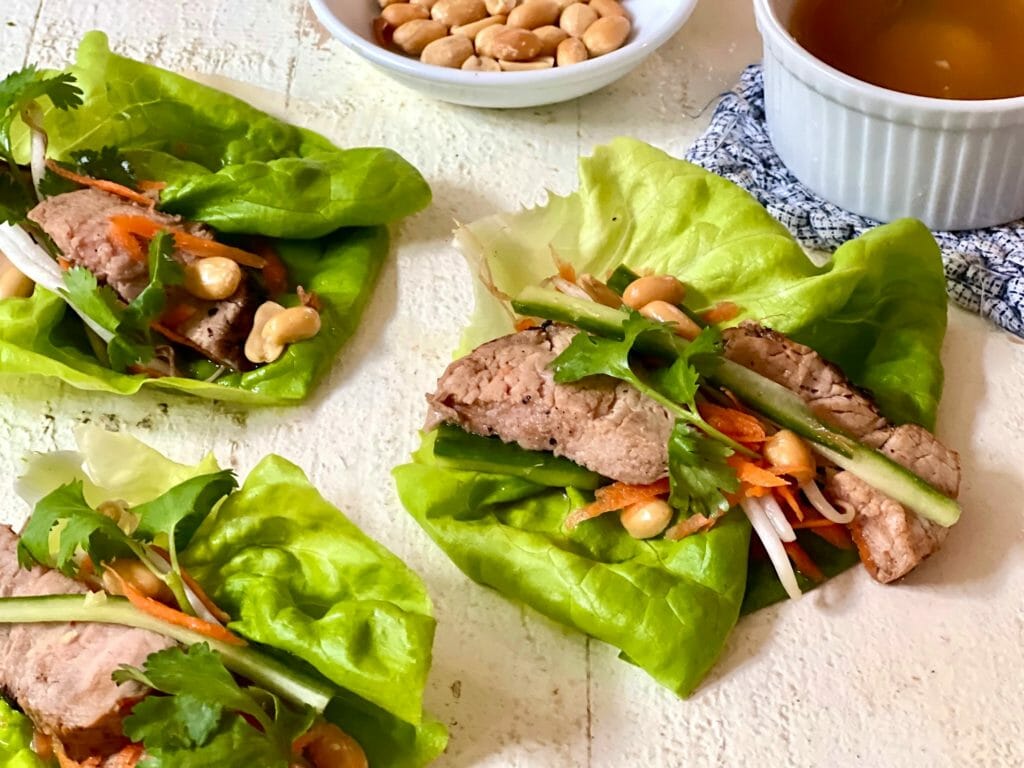 Pork lettuce wraps with dressing and peanuts on the side