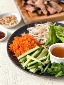 Plate of vegetables and sliced pork for lettuce wraps