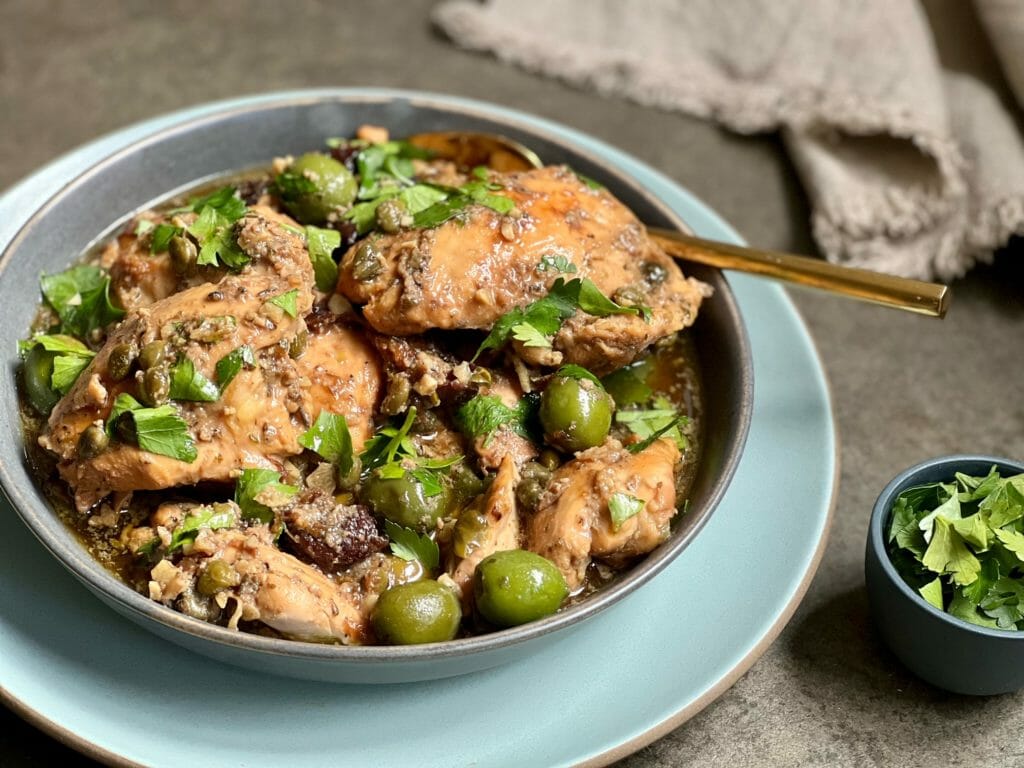 Slow cooker chicken marbella on a plate with parsley garnish