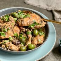 Slow cooker chicken marbella on a plate with parsley garnish