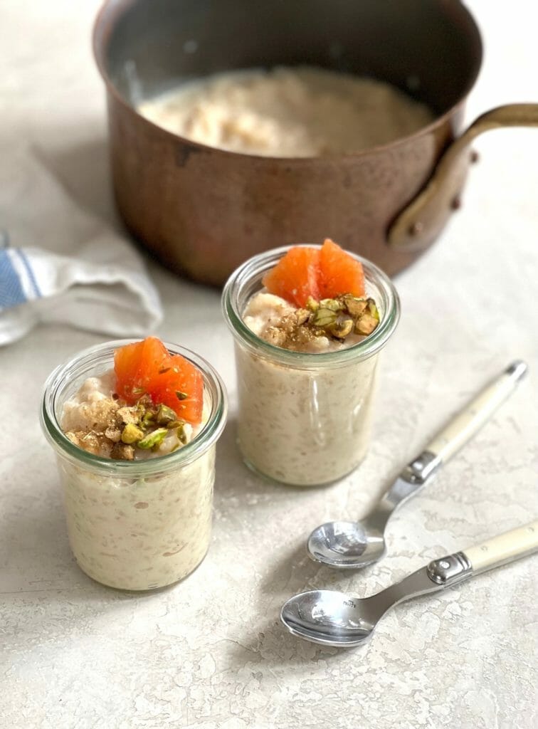 Two glass jars of rice pudding topped with orange and nuts