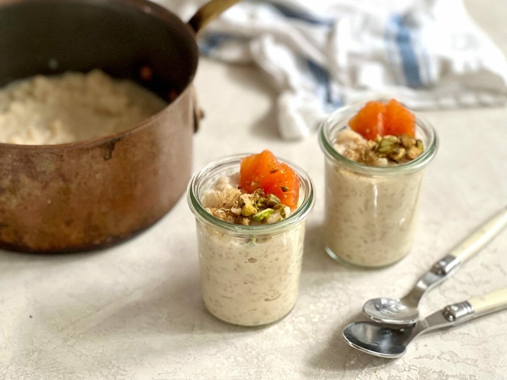 Two glass jars of rice pudding topped with orange and nuts