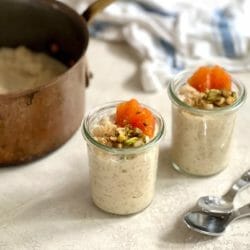 Two glass jars of rice pudding topped with orange and nuts