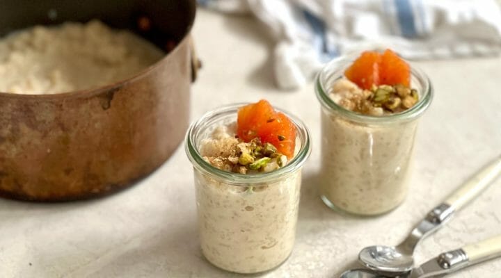 Two glass jars of rice pudding topped with orange and nuts