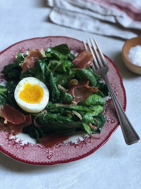 Plate of warm spinach salad with a soft egg