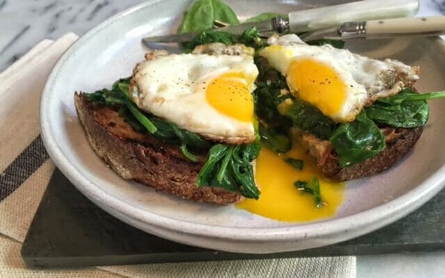 open faced egg sandwich on spinach