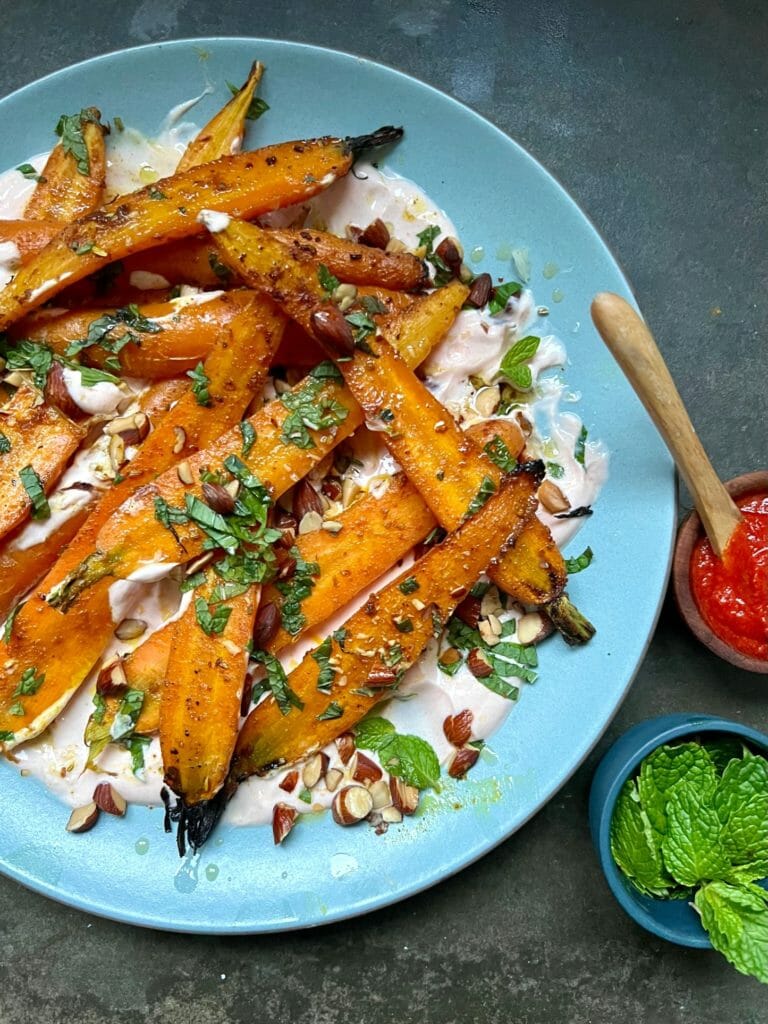 Roasted carrots with harissa yogurt on a blue plate