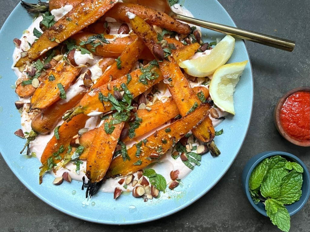 roasted carrots with yogurt with a dish of harissa and mint on the side.