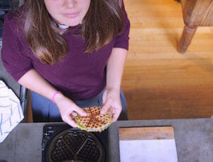 Teen cooking with a waffle