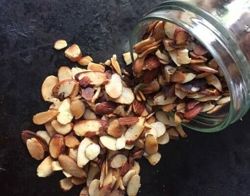 Jar of pan roasted almonds spilling on the counter