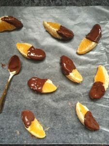 Orange sections dipped in dark chocolate on waxed paper
