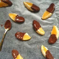 Orange sections dipped in dark chocolate on waxed paper