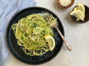 Spaghetti and spiralized zucchini with pesto on a plate with fork
