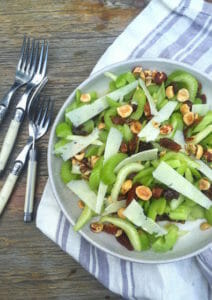 Celery, nut, date, and cheese salad on a plate with a striped napkin and forks