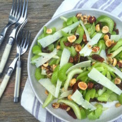 Celery, nut, date, and cheese salad on a plate with a striped napkin and forks