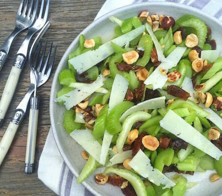 Celery, nut, date, and cheese salad on a plate with a striped napkin and forks