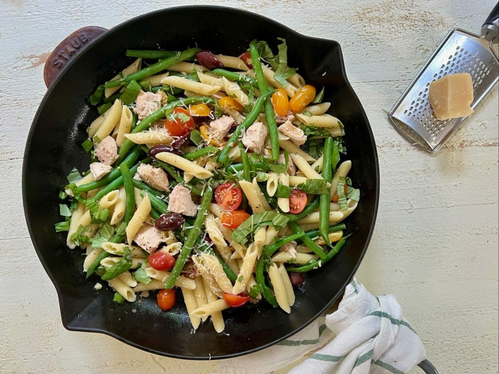 pan of nicoise pasta with Parmesan and cheese grater