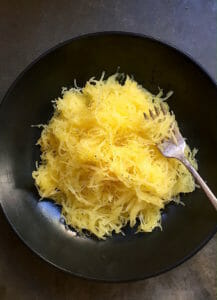 bowl of spaghetti squash in a dark bowl with a fork