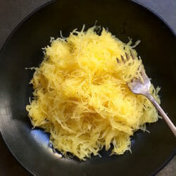bowl of spaghetti squash in a dark bowl with a fork