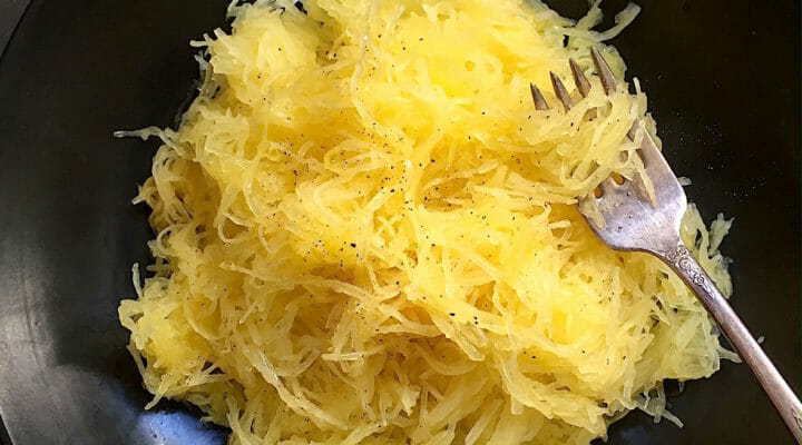 bowl of spaghetti squash in a dark bowl with a fork