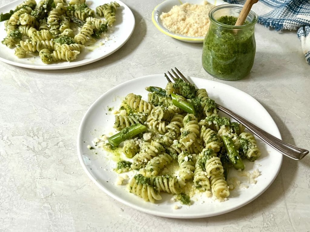 two plates of pasta with pesto and asparagus