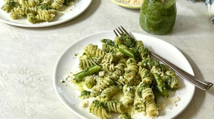 two plates of pasta with pesto and asparagus