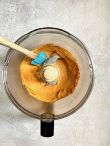 Sweet potato hummus in a food processor with blue spatula