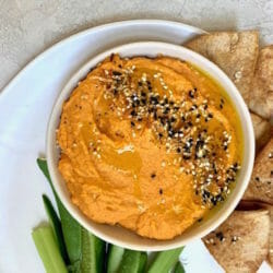 Sweet potato hummus in white bowl with pita chips and vegetables