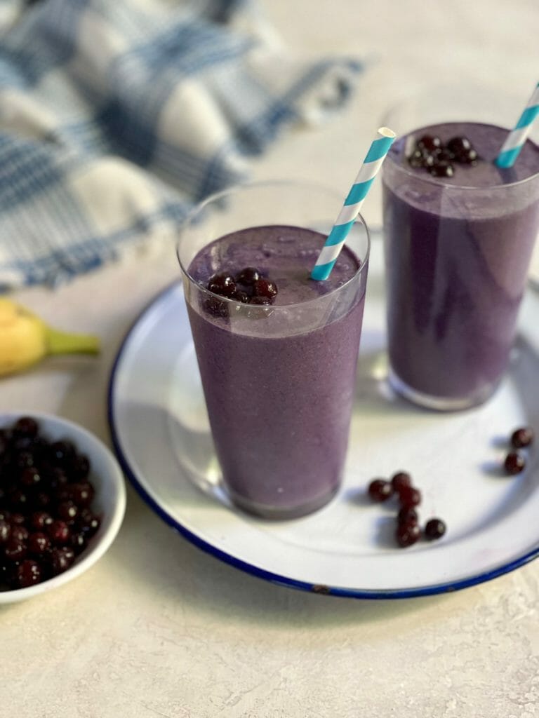 two glasses of wild blueberry smoothie with straws
