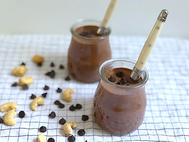 Vegan dark chocolate pudding with cashews and chocolate chips in little jars with spoons