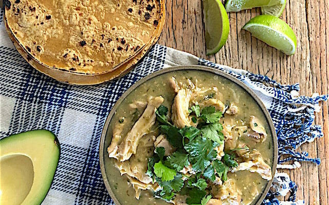 Instant pot chicken in salsa verde with a checked napkin and lime garnish