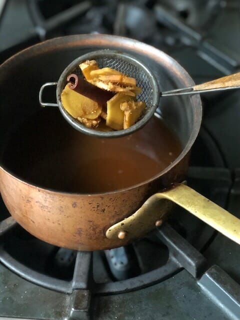 scooping ginger out of pot of chai