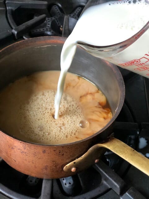 adding milk to pot of tea