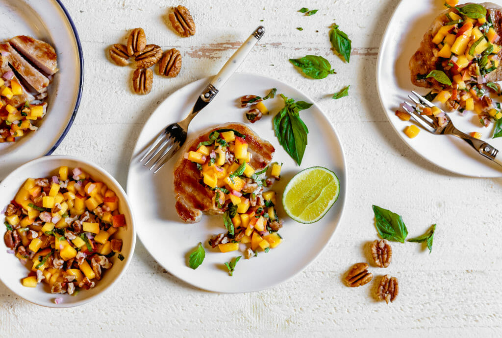 Grilled Pork Chops on a White Plate with Peach Salsa and Fork