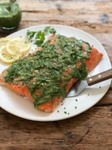 salmon served with green sauce on a white plate or summer vegetable salad served on a plate with a spatula