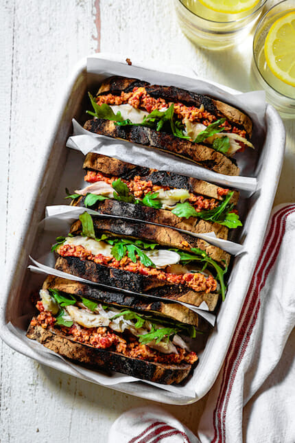 Rotisserie chicken sandwich with muhammara and arugula in white ceramic dish