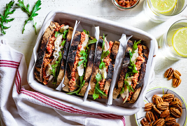 Rotisserie chicken sandwich with muhammara and arugula in white ceramic dish